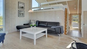 Un salon moderne avec une table basse blanche, un canapé en cuir noir et un parquet en bois.