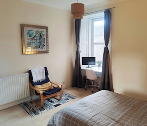 Relax in comfort with a large bed, a cozy chair, and a flat-screen monitor.