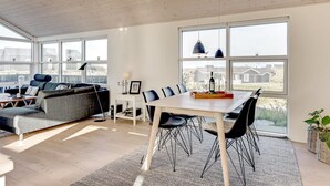 En moderne stue med spiseområde, store vinduer og udsigt til kvarteret.