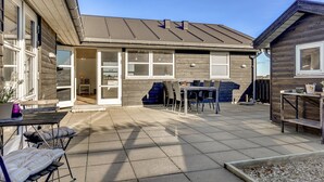 Et moderne hus med en patio, spisebord og udendørs møbler.