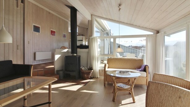 A spacious living area with a large window, a fireplace, and a dining table with chairs.