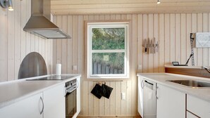 Een moderne keuken met houten lambrisering, een raam met uitzicht op groen en roestvrijstalen apparatuur.