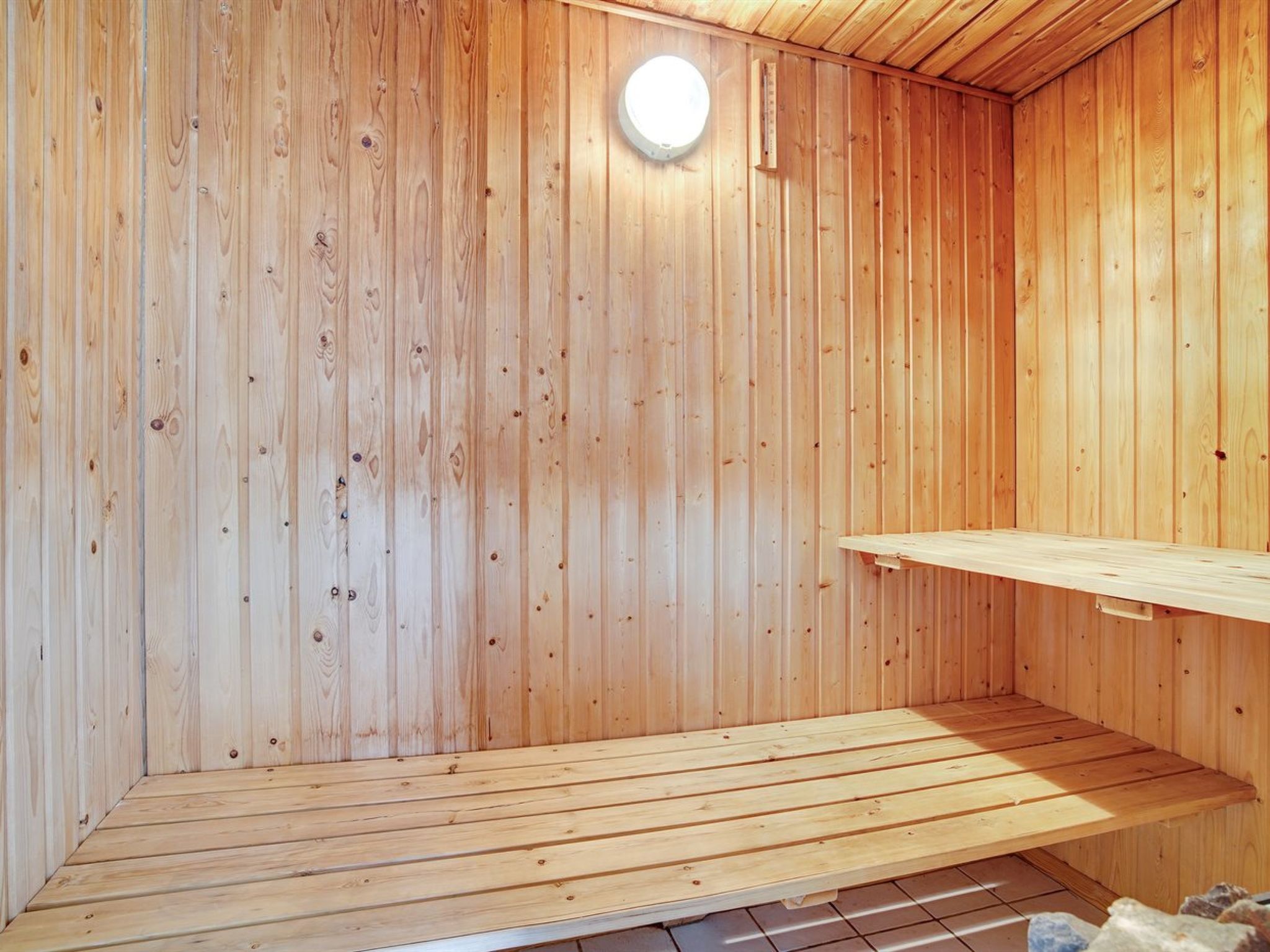 Uma sala de sauna com paredes de madeira e um banco.