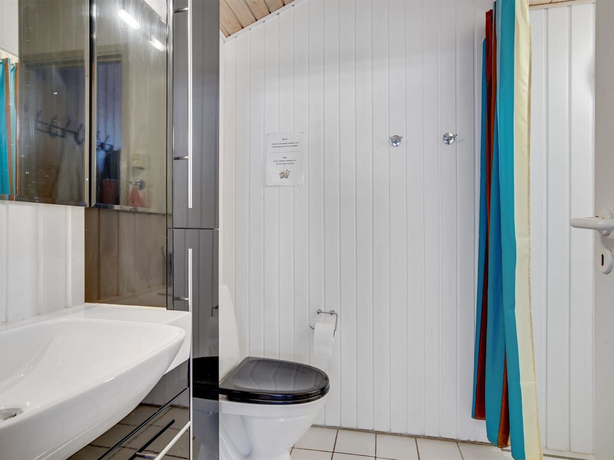 Une salle de bain avec un lavabo blanc, des toilettes et un rideau de douche.