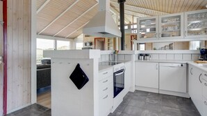 A modern kitchen with white cabinets, a built-in oven, and a large window overlooking a scenic view.