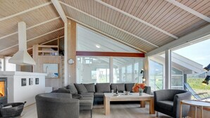 A modern living room with a fireplace, large windows, and a cozy seating area.