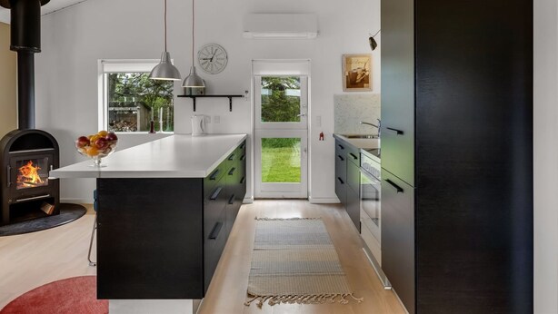 A modern kitchen with a central island, a black stove, and a view to the outdoors. - "Aarthi" - 637m from the sea by Interhome (Hjørring)