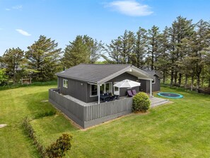 Une maison de plain-pied dotée d’une terrasse, d’un patio avec mobilier d’extérieur et d’un trampoline.