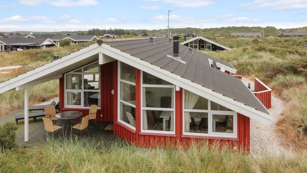 Une maison rouge et blanche avec une grande fenêtre et un espace patio.