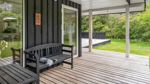 Un espacio al aire libre cubierto con piso de madera, una banca y una mesa.