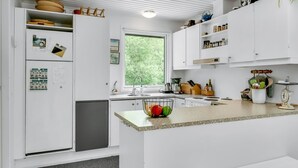 Una cocina moderna con armarios blancos, un lavamanos empotrado y ventana con vistas a la vegetación.