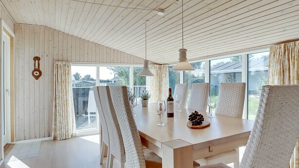 A dining area with a wooden table, white chairs, and pendant lights. - "Afrim" - 694m from the sea by Interhome (Hjørring)