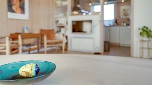 A modern kitchen with white cabinets, a dining area with wooden furniture, and a teal glass bowl on the table. - "Afrim" - 694m from the sea by Interhome (Hjørring)