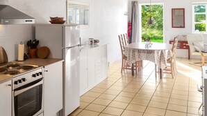 Eine moderne Küche mit weißen Schränken, einem eingebauten Ofen und einem Essbereich mit rundem Tisch und Stühlen.