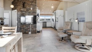 A modern kitchen with a stone wall, stainless steel appliances, and a dining area with a table and chairs.