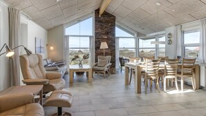 A spacious living area with a large dining table, comfortable seating, and a view of the outdoors.