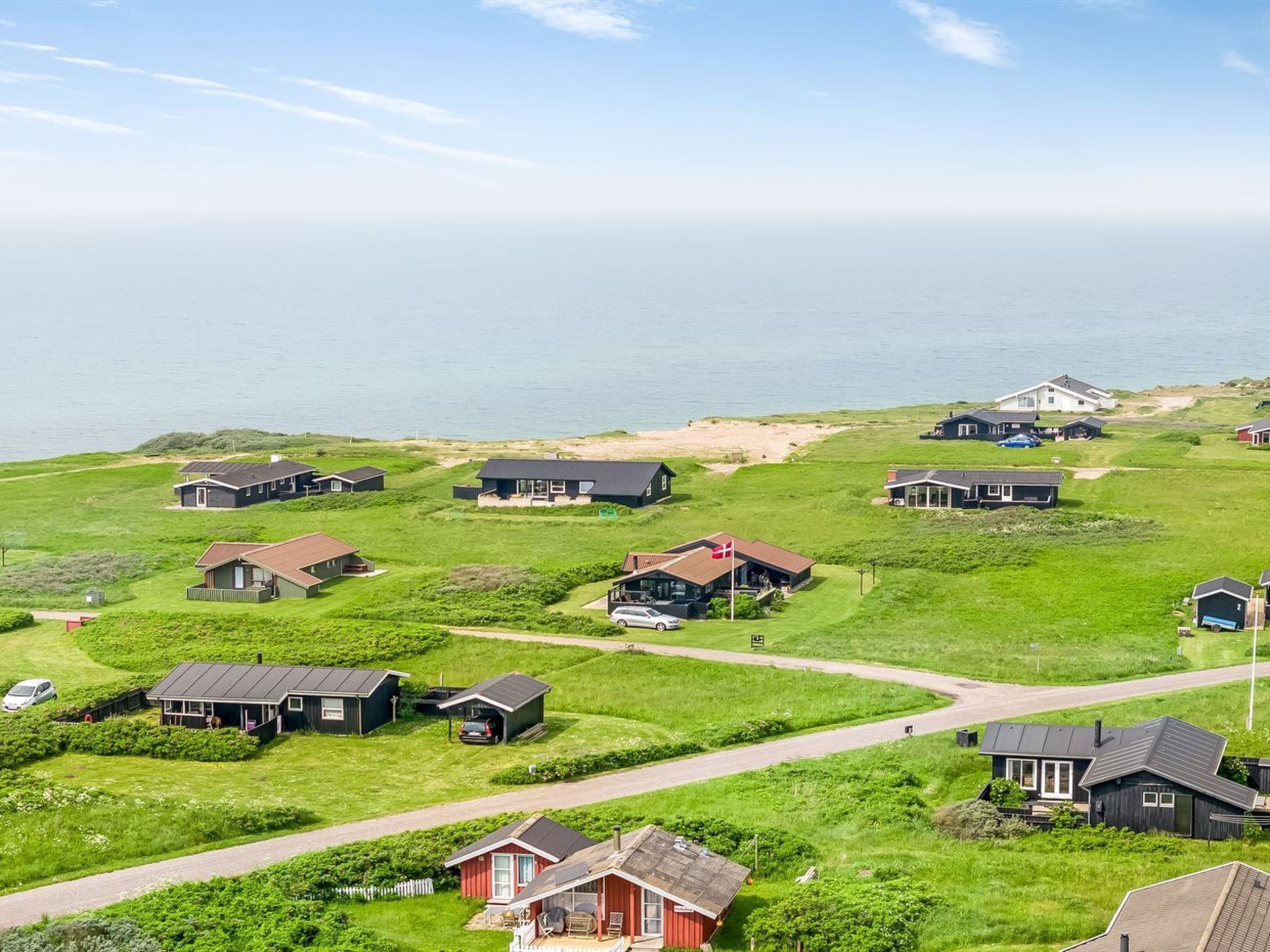 Un quartier résidentiel situé sur la côte, avec des maisons, une route et une vue sur la mer.