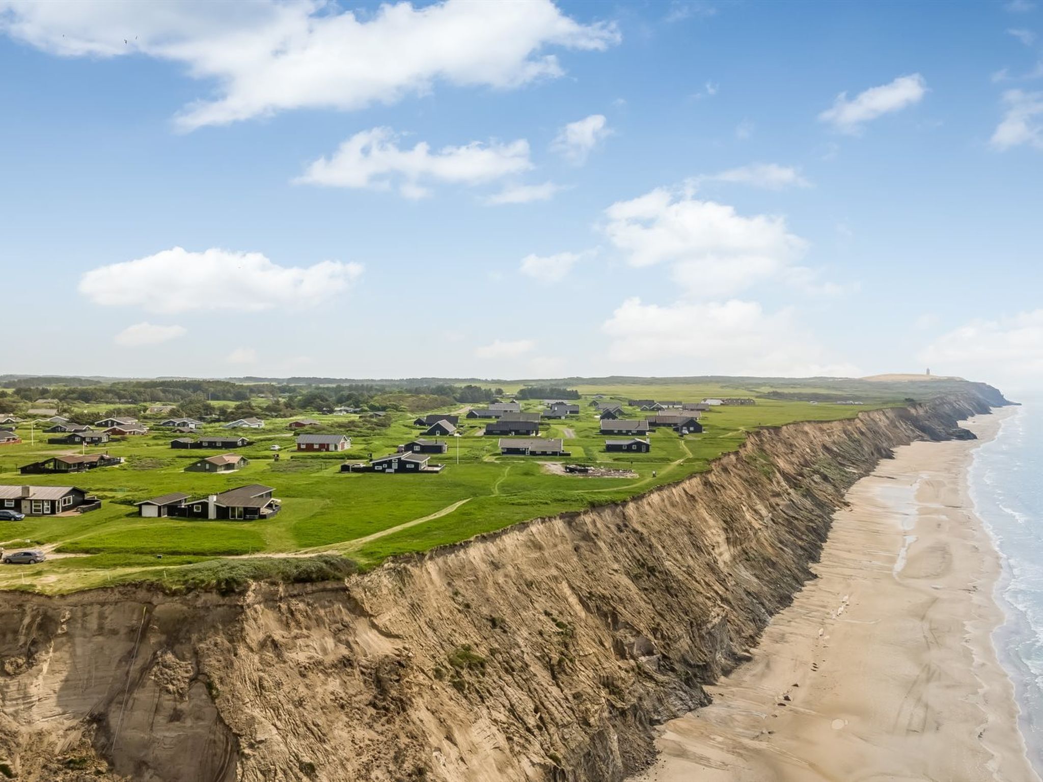 Een kustdorp met huizen op een klif met uitzicht op het strand.
