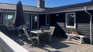 Une terrasse avec une table et des chaises, un parasol et une cheminée.