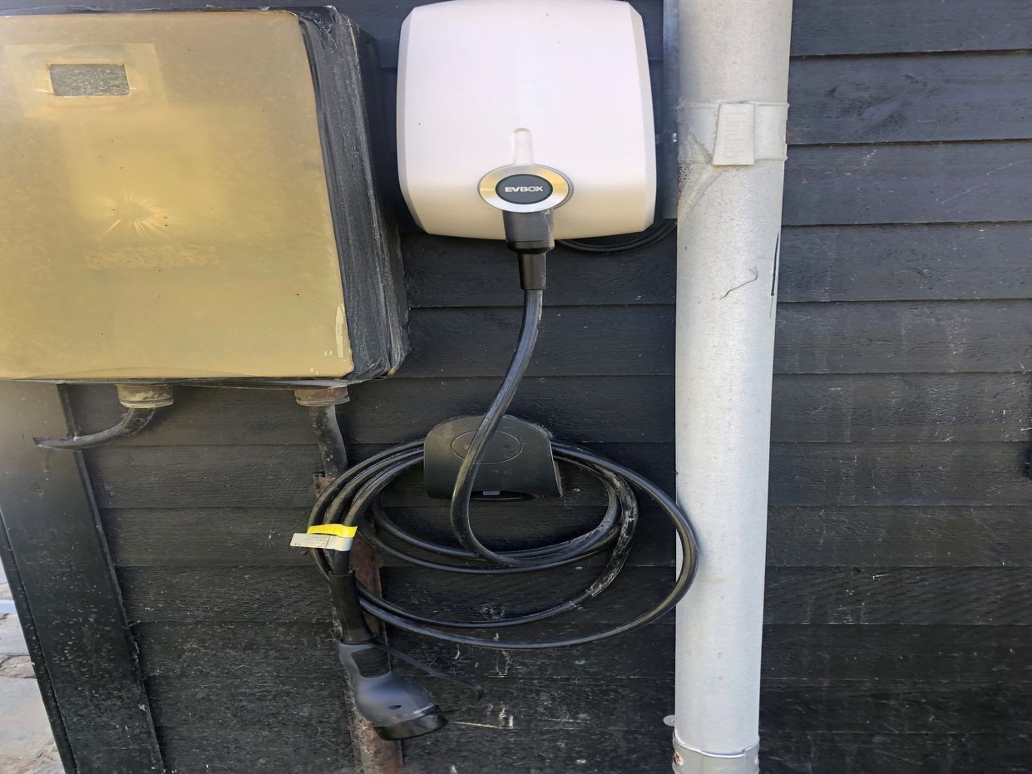 Ein Verteilerkasten, ein weißer Stromkasten und ein schwarzes Kabel, das mit einer Metallrohr verbunden ist.