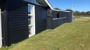 Un bâtiment noir avec une fenêtre blanche et un mât pour drapeau.