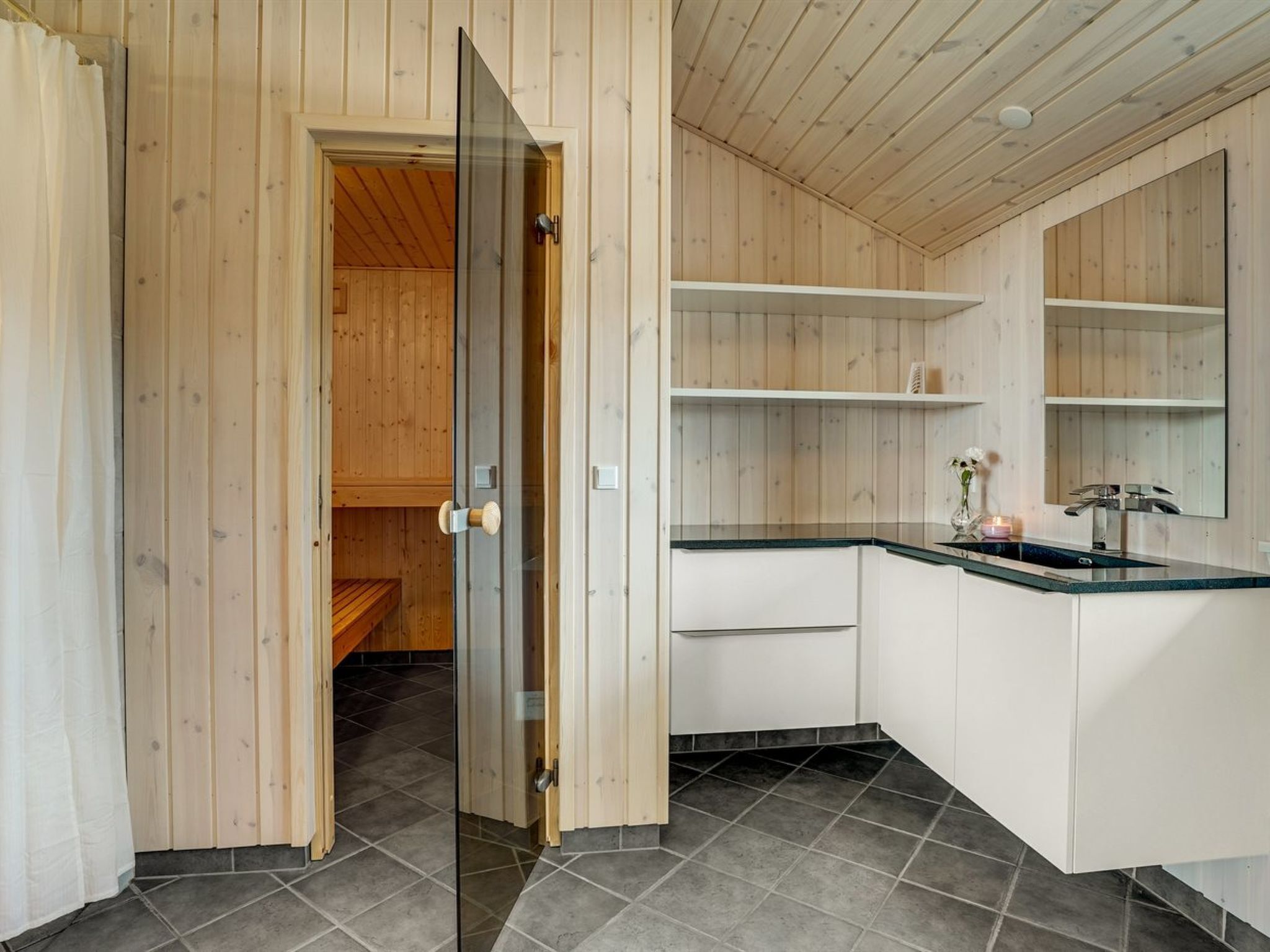 A modern kitchen with wooden paneling, a black countertop, and a sink.