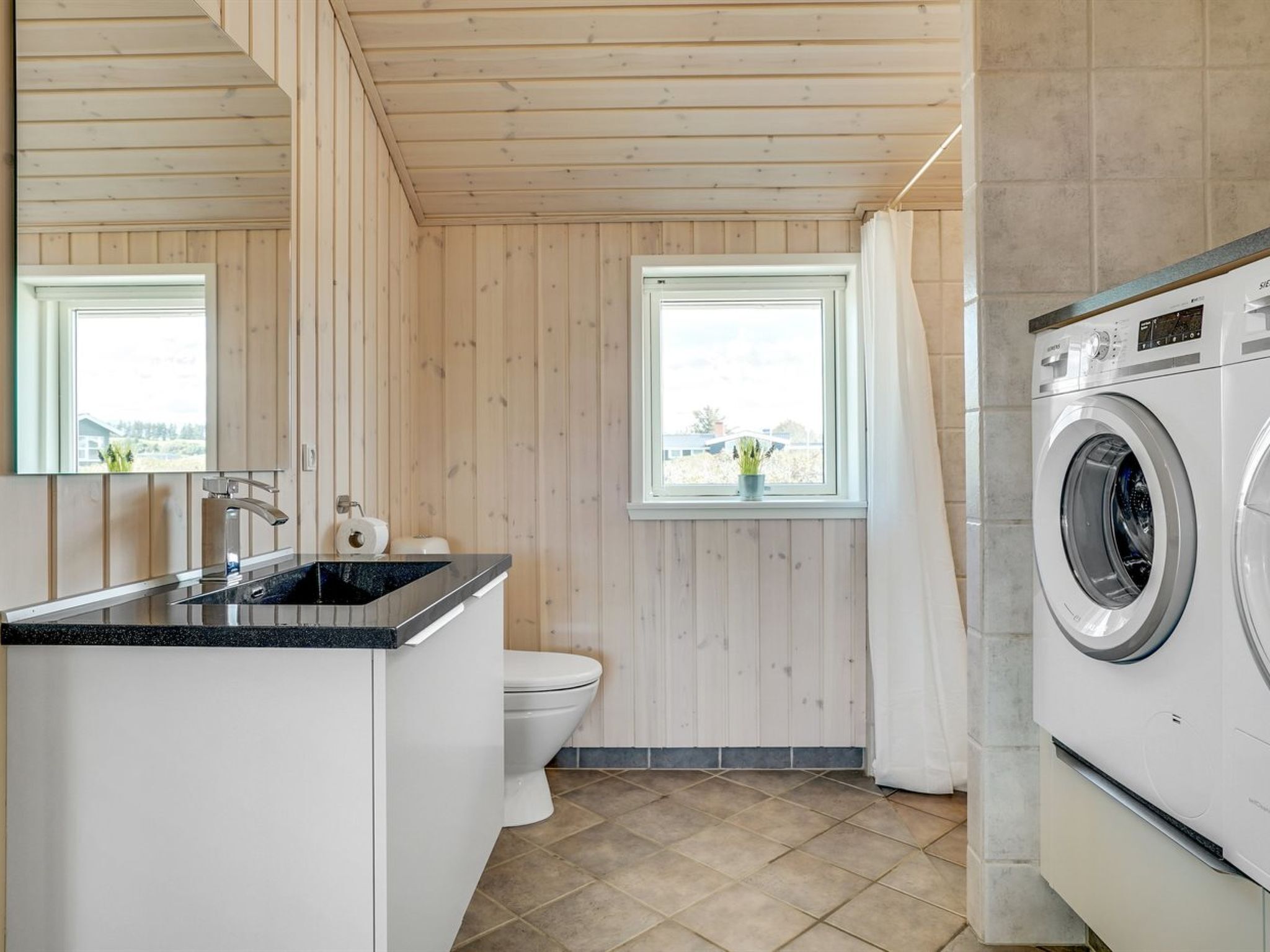 Une petite salle de bain comprenant un lavabo, des toilettes et un lave-linge.