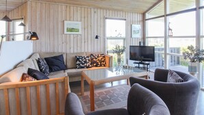 Un salon chaleureux avec des murs lambrissés, un canapé, une table basse et un téléviseur.