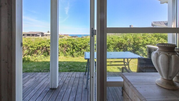 Une terrasse ouverte offrant une vue sur l’océan et la végétation.