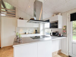 Una cocina moderna con armarios blancos, una campana extractora de acero inoxidable, microondas integrado y una isla grande con pileta.