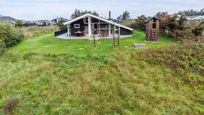 A modern house with a large deck, a wooden shed, and a grassy yard. - "Herbiorn" - 403m from the sea by Interhome (Hjørring)