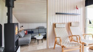A cozy living room with a fireplace, a grey sofa, two wicker chairs, and a small round table with a plant. - "Herbiorn" - 403m from the sea by Interhome (Hjørring)