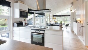 A modern kitchen with white cabinetry, a built-in oven, and a large island with a sink. - "Herbiorn" - 403m from the sea by Interhome (Hjørring)
