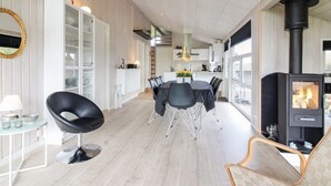 A modern kitchen with white cabinets, a dining area with a round table and chairs, and a wood-burning stove. - "Herbiorn" - 403m from the sea by Interhome (Hjørring)