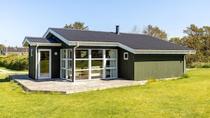 A modern house with a large glass door, a covered porch, and a metal roof. - "Freija" - 719m from the sea by Interhome (Hjørring)