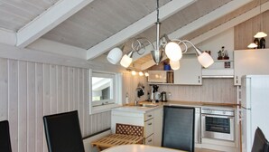 Una cocina moderna con armarios blancos, una mesa de comedor de madera y una lámpara colgante.
