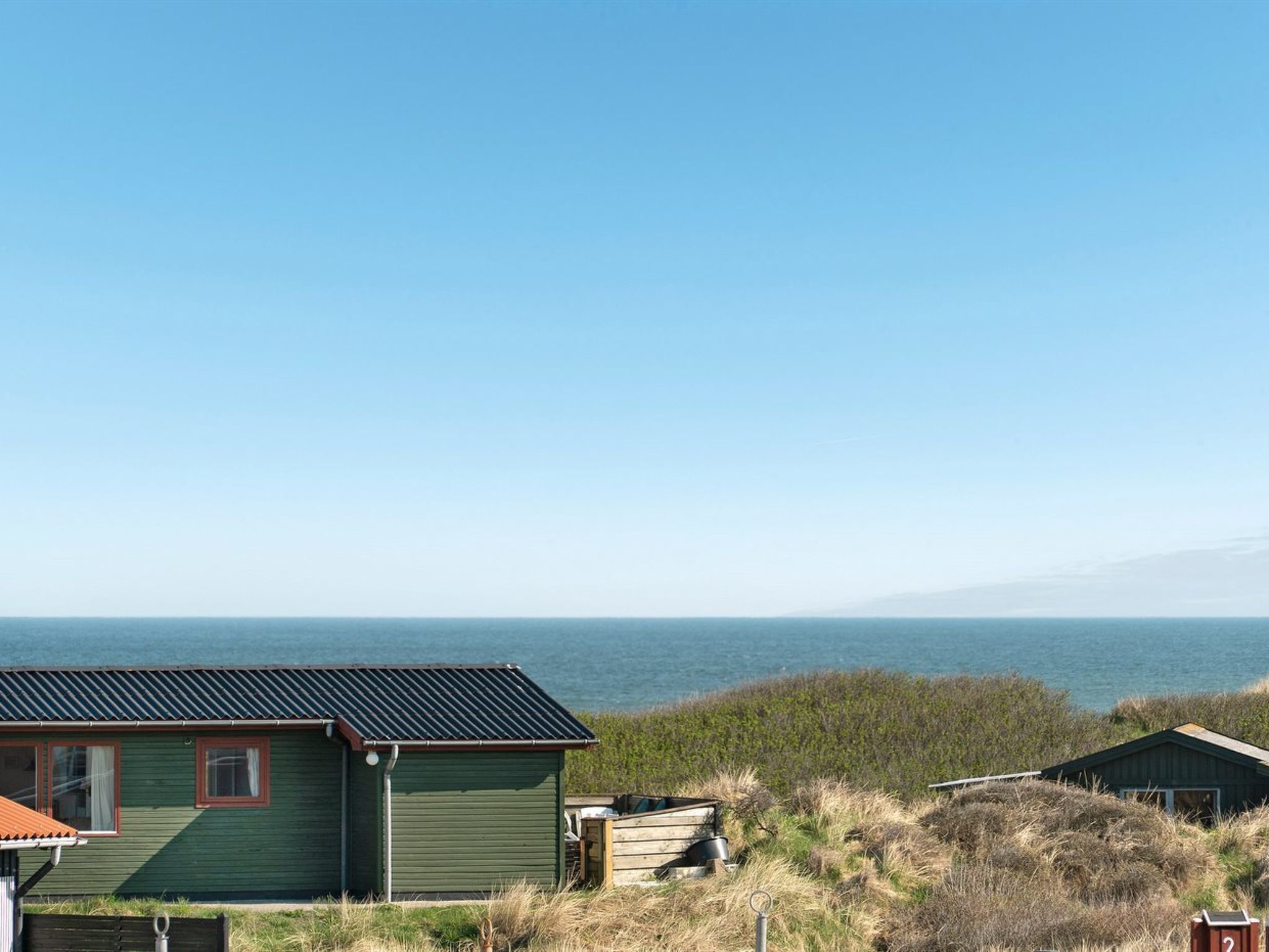 Une propriété située sur la côte, dotée d’un bâtiment écologique, d’un bateau en bois et offrant une vue sur la mer.