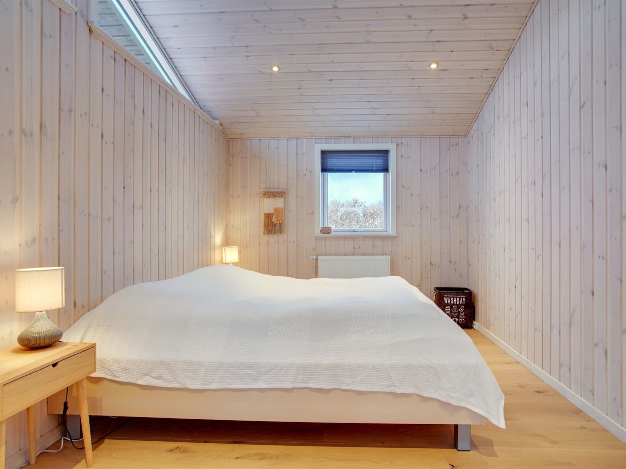 A bedroom with a bed, bedside lamp, and a small table.