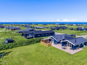 Zona residencial costera con casas modernas, una terraza de madera y vista al mar.