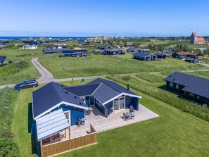 Uma área residencial moderna com casas, uma igreja e vista clara para o mar.