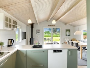 A modern kitchen with a central island, a built-in stove, and a dining area with a table and chairs.