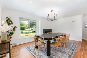 A dining room with a large table, wooden chairs, a chandelier, a fireplace, and a view of the outdoors. - Cozy 3BR Home 4 Min From ND (SOuth Bend)