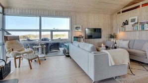 Een gezellige woonkamer met een groot raam, een bank, een stoel en een televisie.