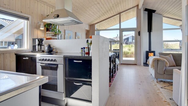 Een moderne keuken met een groot fornuis, oven en een ingebouwde grill. Er is een zithoek met een bank en een open haard.