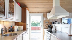 Une cuisine moderne avec des armoires blanches, des appareils en acier inoxydable et un plafond en bois.
