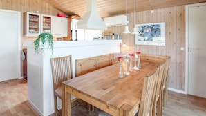 Un intérieur en bois avec un îlot central, des chaises en bois et une table à manger.
