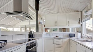 Eine moderne Küche mit weißen Schränken, einem eingebauten Backofen, einer Mikrowelle und einem Spülbecken.