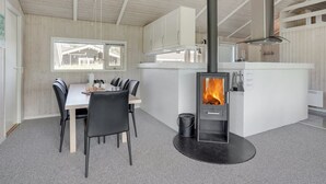 Eine moderne Küche mit einer zentralen Kochinsel, einem Esstisch mit Stühlen und einem Holzofen.