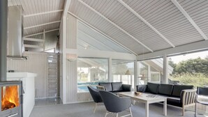 Ein moderner Außenbereich mit Kamin, Sitzgelegenheiten und Blick auf einen Pool.