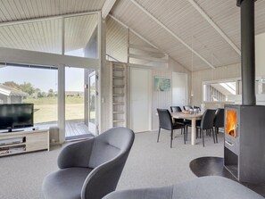 A modern living room with a fireplace, a television, and a dining area with chairs and a table. - "Serine" - 800m from the sea by Interhome (Hjørring)